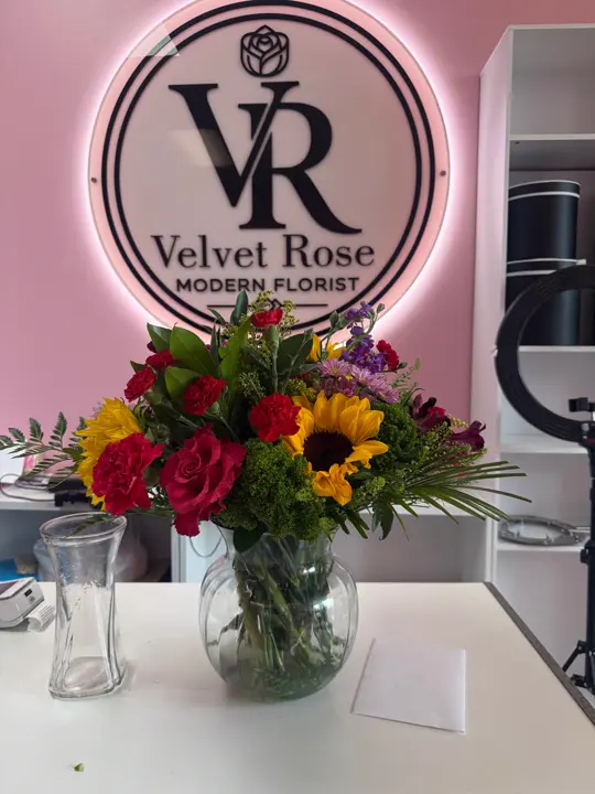 Sunflower and rose vase under the Velvet Rose sign